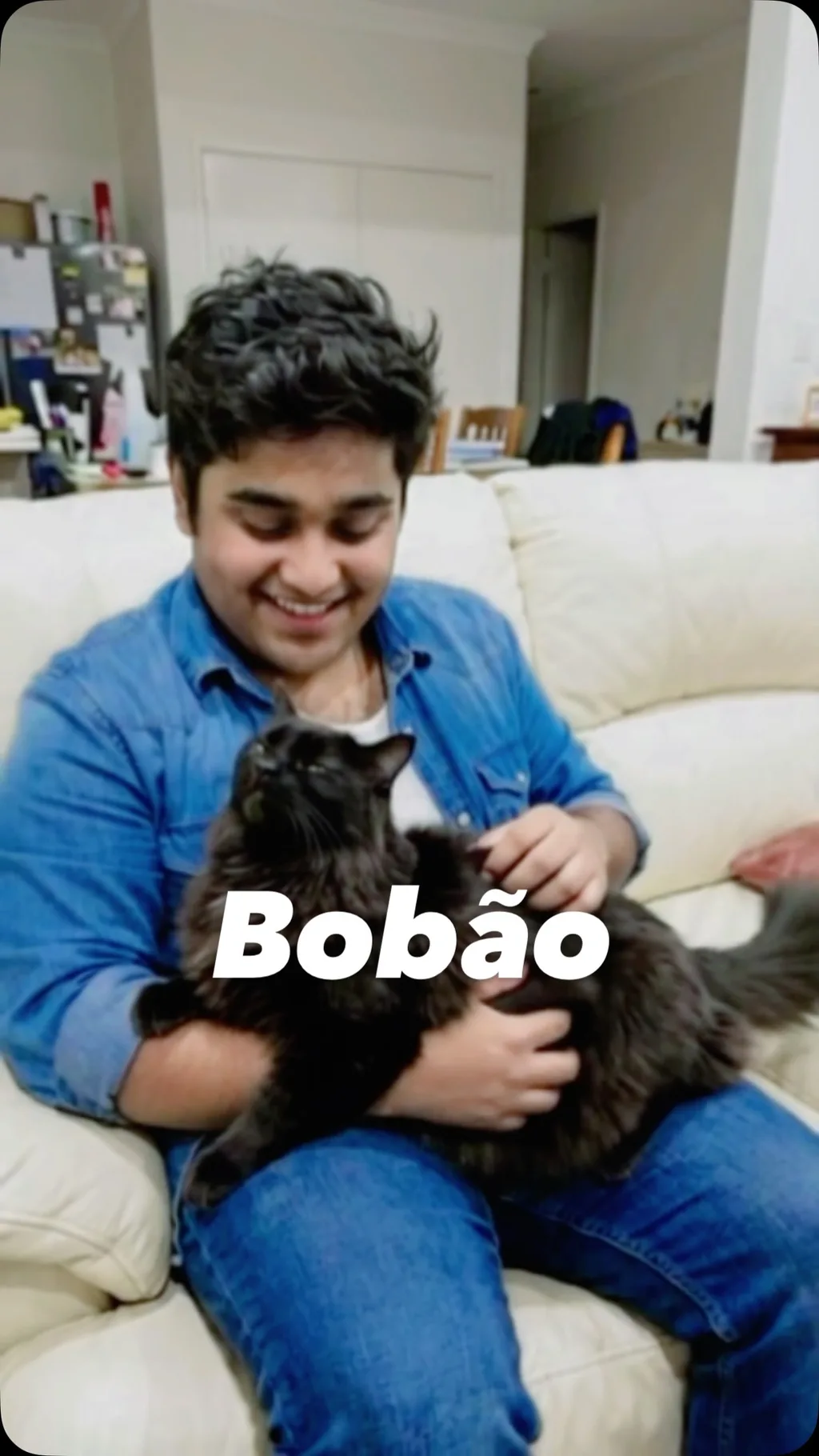 Integrante da banda com um gato no sofá, na arte Bobão